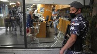 Seorang polisi Lebanon berjaga di samping jendela bank yang dirusak oleh para nasabah untuk keluar dari bank setelah menyerangnya. Sekitar tiga perempat dari populasi telah jatuh ke dalam kemiskinan karena ekonomi negara Mediterania kecil itu masuk krisis berkepanjangan.