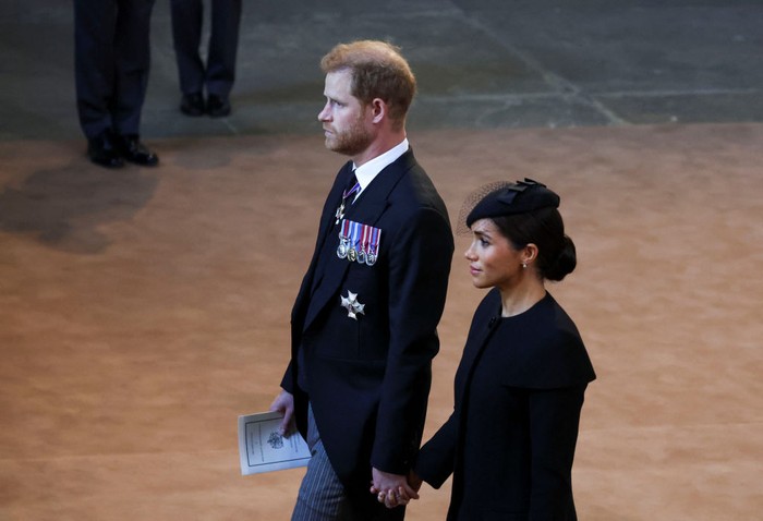 Pangeran Harry dan Meghan Markle gandengan tangan LONDON, ENGLAND - SEPTEMBER 14: Prince Harry and Meghan, Duchess of Sussex walk as procession with the coffin of Britain's Queen Elizabeth arrives at Westminster Hall from Buckingham Palace for her lying in state on September 14, 2022 in London, United Kingdom. Queen Elizabeth II's coffin is taken in procession on a Gun Carriage of The King's Troop Royal Horse Artillery from Buckingham Palace to Westminster Hall where she will lay in state until the early morning of her funeral. Queen Elizabeth II died at Balmoral Castle in Scotland on September 8, 2022, and is succeeded by her eldest son, King Charles III. (Photo by Phil Noble - WPA Pool/Getty Images)