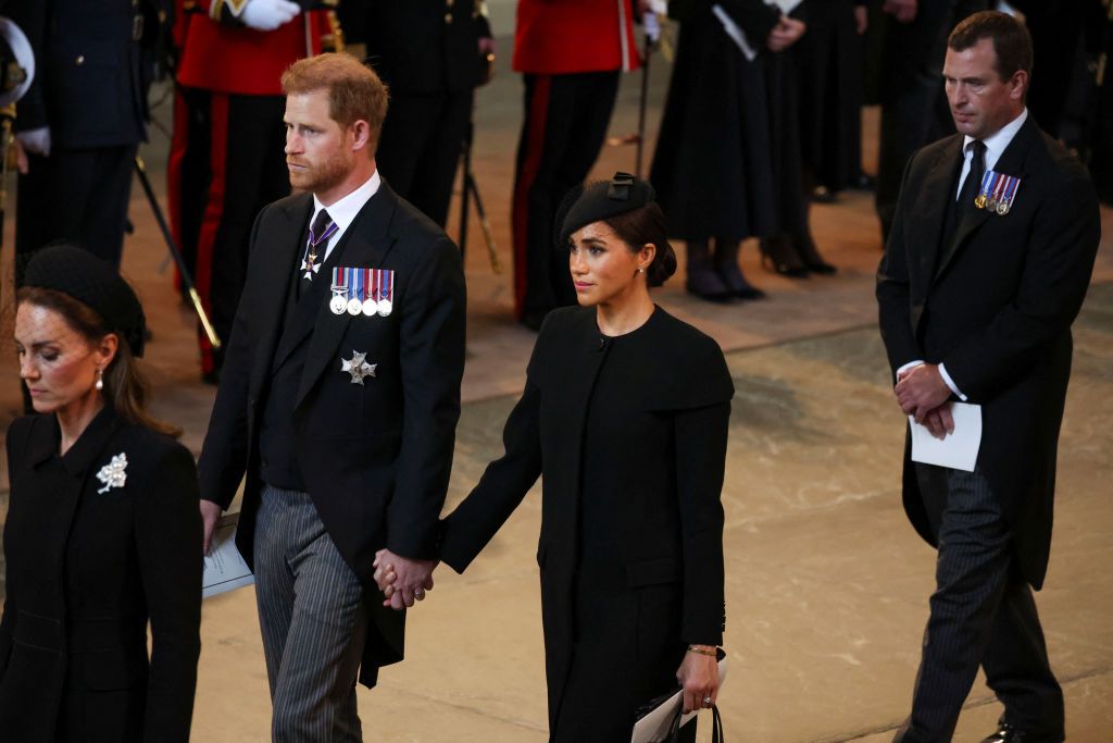 LONDON, ENGLAND - SEPTEMBER 14: Prince Harry and Meghan, Duchess of Sussex walk as procession with the coffin of Britain's Queen Elizabeth arrives at Westminster Hall from Buckingham Palace for her lying in state on September 14, 2022 in London, United Kingdom. Queen Elizabeth II's coffin is taken in procession on a Gun Carriage of The King's Troop Royal Horse Artillery from Buckingham Palace to Westminster Hall where she will lay in state until the early morning of her funeral. Queen Elizabeth II died at Balmoral Castle in Scotland on September 8, 2022, and is succeeded by her eldest son, King Charles III. (Photo by Phil Noble - WPA Pool/Getty Images)