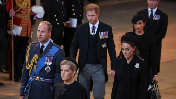 Pangeran Harry dan Meghan Markle gandengan tangan LONDON, ENGLAND - SEPTEMBER 14: Prince Harry and Meghan, Duchess of Sussex walk as procession with the coffin of Britain's Queen Elizabeth arrives at Westminster Hall from Buckingham Palace for her lying in state on September 14, 2022 in London, United Kingdom. Queen Elizabeth II's coffin is taken in procession on a Gun Carriage of The King's Troop Royal Horse Artillery from Buckingham Palace to Westminster Hall where she will lay in state until the early morning of her funeral. Queen Elizabeth II died at Balmoral Castle in Scotland on September 8, 2022, and is succeeded by her eldest son, King Charles III. (Photo by Phil Noble - WPA Pool/Getty Images)