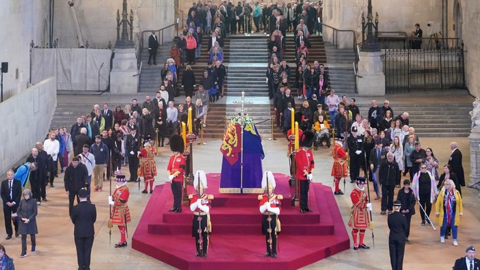 LONDON, ENGLAND - SEPTEMBER 16:  Members of the public file past the coffin of Queen Elizabeth II, draped in the Royal Standard with the Imperial State Crown and the Sovereigns orb and sceptre, lying in state on the catafalque in Westminster Hall, at the Palace of Westminster, ahead of her funeral on Monday, on September 16, 2022 in London, England. Members of the public are able to pay respects to Her Majesty Queen Elizabeth II for 23 hours a day until 06:30 on September 19, 2022.  Queen Elizabeth II died at Balmoral Castle in Scotland on September 8, 2022, and is succeeded by her eldest son, King Charles III. (Photo by Yui Mok - WPA Pool/Getty Images)
