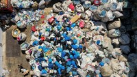 Seorang pekerja berjalan melewati tumpukan sampah di fasilitas pemilahan dan daur ulang Lebanon Waste Management di Bauchrieh. Pada bulan Juni 2022 kemarin, ia meluncurkan layanan Drive Throw, di mana orang mengendarai mobil mereka untuk membuang sampah termasuk logam, plastik dan kertas dengan imbalan uang tunai yang sangat dibutuhkan.