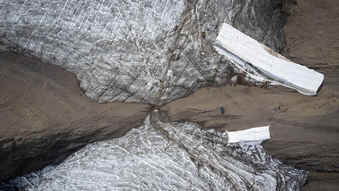 Duh, Lapisan Es di Celah Pegunungan Swiss Mencair This picture taken on September 13, 2022 at the Glacier 3000 resort above Les Diablerets shows tourists walking on the Tsanfleuron pass free of the ice that covered it for at least 2,000 years. - The thick layer of ice that has covered a Swiss mountain pass between Scex Rouge glacier and Tsanfleuron glacier since at least the Roman era has melted away completely. Following a dry winter, the summer heatwaves hitting Europe have been catastrophic for the Alpine glaciers, which have been melting at an accelerated rate. (Photo by Fabrice COFFRINI / AFP) (Photo by FABRICE COFFRINI/AFP via Getty Images)