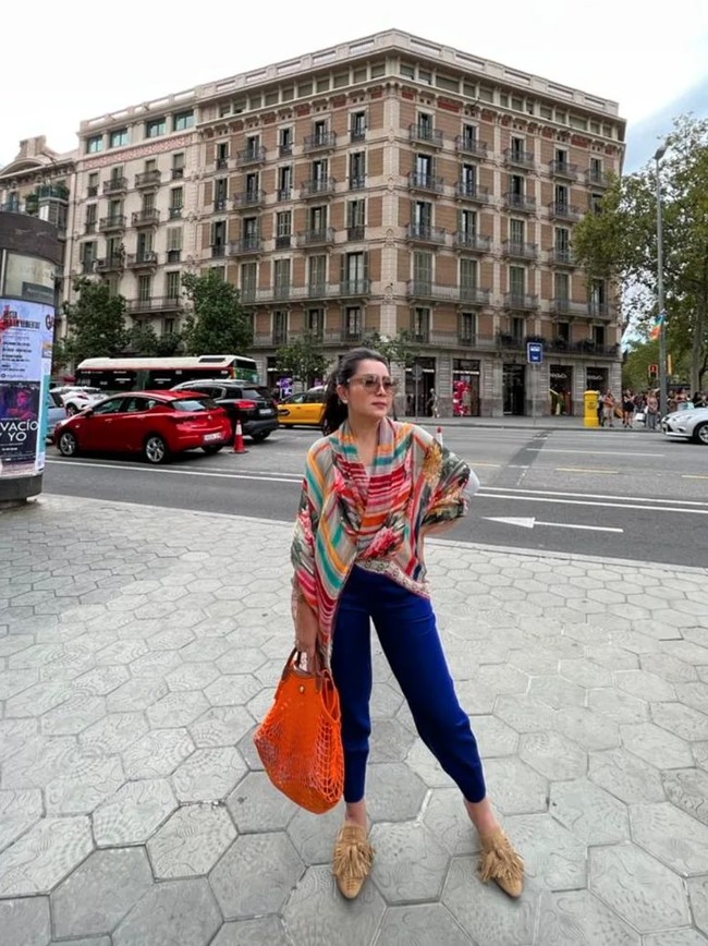Ada kalanya Mayangsari mengenakan busana casual selama di Eropa. Seperti di dalam foto, dirinya tampak memadukan blouse berwarna-waarni dengan celana panjang berwarna biru. Foto: Instagram/@mayangsari_official