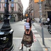 Terlihat santai dan feminin, Mayangsari memadukan kaos putih bermotif dengan sebuah rok panjang unik yang dibuat dari beberapa motif berbeda. Agar terlihat lebih stylish, Mayangsari menambahkan penampilannya dengan kaca mata hitam dan sandal mules. Foto: Instagram/@mayangsari_official