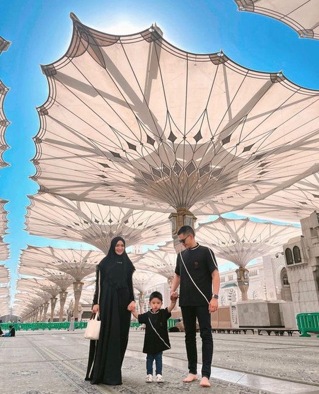 Citra Kirana, Rezky Aditya dan Keene Atharrazka kompak memakai busana serba hitam saat berada di Masjid Nabawi. Citra mengenakan hijab khimar hitam dan dress dengan list putih. Rezky dan Athar memakai atasan dengan motif yang sama. Foto: Dok. Instagram @thereal_rezkyadhitya.