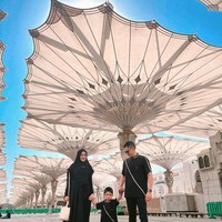 Citra Kirana, Rezky Aditya dan Keene Atharrazka kompak memakai busana serba hitam saat berada di Masjid Nabawi. Citra mengenakan hijab khimar hitam dan dress dengan list putih. Rezky dan Athar memakai atasan dengan motif yang sama. Foto: Dok. Instagram @thereal_rezkyadhitya.