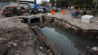 Pengguna jalan melintas di dekat pengerjaan saluran air air di Jalan Ambengan, Surabaya, Jawa Timur, Jumat (16/9/2022).