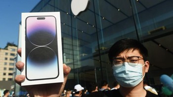 Seorang konsumen menunjukkan kemasan iPhone 14 yang baru saja dibelinya. Foto: Getty Images