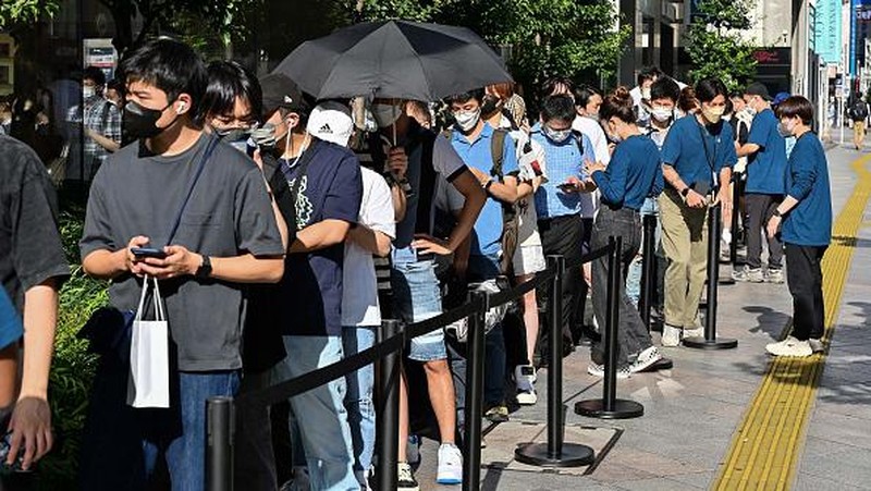 Members of security stand at the entrance to an Apple store as customers queue up for the launch of the new iPhone 14 in Tokyo on September 16, 2022. (Photo by Richard A. Brooks / AFP) (Photo by RICHARD A. BROOKS/AFP via Getty Images)