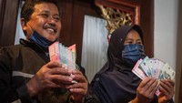 Ekspresi bahagia terlihat di wajah Samin. Uang rusak yang dimakan rayap milik Samin diganti dengan uang baru emisi 2022 senilai Rp 20.220.000.  