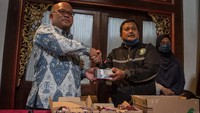 Samin menerima uang baru dari Kepala Kantor Perwakilan Bank Indonesia (BI) Solo, Nugroho Joko Prastowo (kiri) saat menukarkan uang rusak miliknya yang dimakan rayap di kantor Perwakilan BI, Solo, Jawa Tengah, Kamis (15/9/2022).   