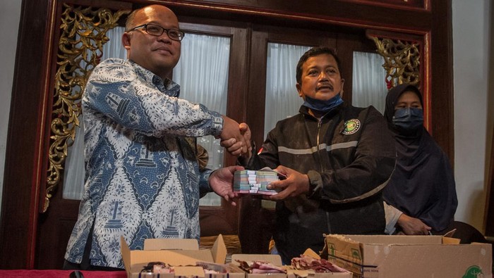 Semringah Samin Saat BI Solo Ganti Uangnya yang Dimakan Rayap Kepala Kantor Perwakilan Bank Indonesia Solo Nugroho Joko Prastowo (kiri) menyerahkan uang baru pengganti kepada Samin (kedua kanan) dan istri Sri Kadarwati (kanan) saat menukarkan uang rusak miliknya yang dimakan rayap di kantor Perwakilan Bank Indonesia, Solo, Jawa Tengah, Kamis (15/9/2022). Bank Indonesia Solo mengganti uang rusak yang dimakan rayap milik Samin dengan uang baru emisi 2022 senilai Rp20.220.000 setelah diidentifikasi memenuhi persyaratan penukaran uang rusak seperti tanda keaslian uang kertas masih dapat dikenali dan fisik uang kertas masih ada dua pertiga dari ukuran aslinya. ANTARA FOTO/Mohammad Ayudha/rwa.