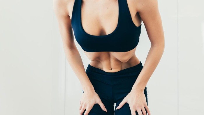 Yoga nauli kriya Vacuum for the abdomen pulling. Close up photo part of the body of a young beautiful sports woman standing and performing the exercise of pulling the abdomen in black sportswear