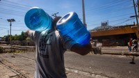 Orang-orang membawa botol air untuk diisi ulang saat pengunjuk rasa melanjutkan demonstrasi pada hari ketiga mobilisasi atas kenaikan harga bahan bakar di Port-au-Prince, Haiti pada 15 September 2022.