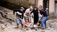 Warga berusaha membersihkan lumpur dari jalan dalam proses evakuasi seorang Lansia.