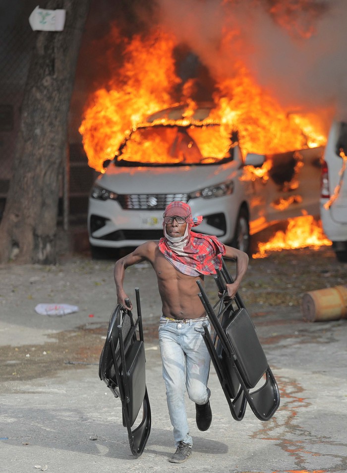 Melihat Lagi Mobil-mobil yang Dibakar Gegara Demo BBM di Haiti An armed man stands near a burnt car during protests over rising fuel prices and crime as inflation surged to its highest in a decade, in Port-au-Prince, Haiti September 14, 2022. REUTERS/Ralph Tedy Erol