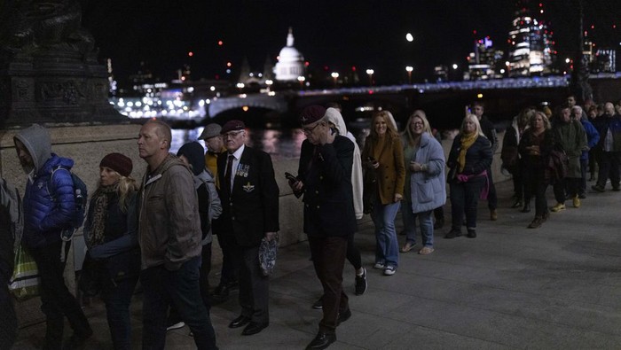 LONDON, ENGLAND - SEPTEMBER 17: Members of the public file past Queen Elizabeth IIs flag-draped casket lying in state on the catafalque as they enter Westminster Hall in the middle of the night on September 17, 2022 in London, England. Members of the public are able to pay respects to Her Majesty Queen Elizabeth II for 23 hours a day from 17:00 on September 17, 2022 until 06:30 on September 19, 2022.  Queen Elizabeth II died at Balmoral Castle in Scotland on September 8, 2022, and is succeeded by her eldest son, King Charles III. (Photo by Chip Somodevilla/Getty Images)