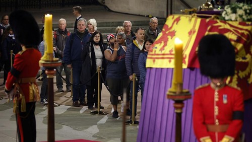 LONDON, ENGLAND - SEPTEMBER 17: Members of the public file past Queen Elizabeth IIs flag-draped casket lying in state on the catafalque as they enter Westminster Hall in the middle of the night on September 17, 2022 in London, England. Members of the public are able to pay respects to Her Majesty Queen Elizabeth II for 23 hours a day from 17:00 on September 17, 2022 until 06:30 on September 19, 2022.  Queen Elizabeth II died at Balmoral Castle in Scotland on September 8, 2022, and is succeeded by her eldest son, King Charles III. (Photo by Chip Somodevilla/Getty Images)