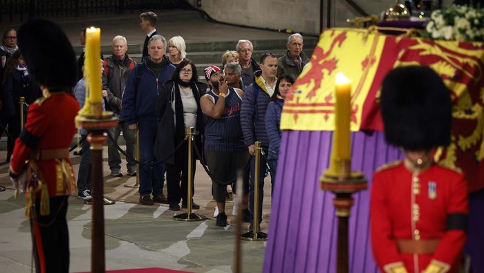 LONDON, ENGLAND - SEPTEMBER 17: Members of the public file past Queen Elizabeth II's flag-draped casket lying in state on the catafalque as they enter Westminster Hall in the middle of the night on September 17, 2022 in London, England. Members of the public are able to pay respects to Her Majesty Queen Elizabeth II for 23 hours a day from 17:00 on September 17, 2022 until 06:30 on September 19, 2022. Queen Elizabeth II died at Balmoral Castle in Scotland on September 8, 2022, and is succeeded by her eldest son, King Charles III. (Photo by Chip Somodevilla/Getty Images)