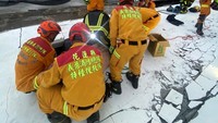Petugas pemadam kebakaran berusaha mengevakuasi warga yang terjebak di reruntuhan gedung.