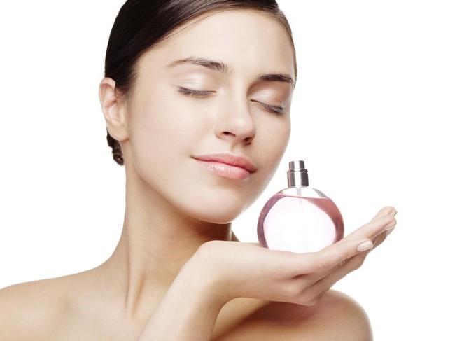 young female smelling a bottle of perfume