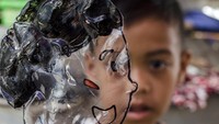 Seorang anak menunjukkan wayang yang terbuat dari plastik saat kegiatan lokakarya di Kampung Cibogo, Bandung, Jawa Barat, Minggu (18/9/2022).