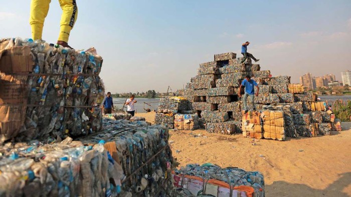 An environmental volunteer helps build a pyramid made of plastic waste collected from the Nile river, as part of an event to raise awareness on pollution on 
