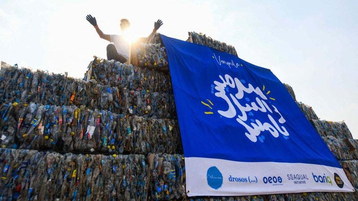 An environmental volunteer helps build a pyramid made of plastic waste collected from the Nile river, as part of an event to raise awareness on pollution on 