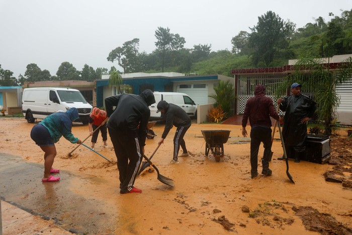 People clean debris from a road after a mudslide caused by Hurricane Fiona in Cayey, Puerto Rico, Sunday, Sept. 18, 2022. (AP Photo/Stephanie Rojas)