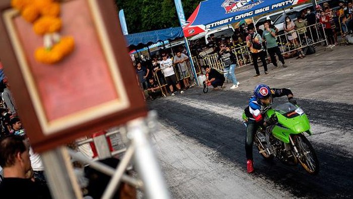 Brumm.. Adu Kebut Balap Drag Bike di Thailand yang Menantang This photo taken on September 11, 2022 shows a Thai youth doing a wheelie with his electric bike during the NGO Street Drag Race event in Thailand's Chonburi province. (Photo by MANAN VATSYAYANA / AFP) (Photo by MANAN VATSYAYANA/AFP via Getty Images)