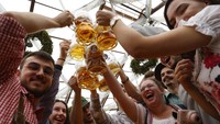 Orang-orang bersorak dengan bir saat pembukaan resmi festival bir terbesar di dunia, Oktoberfest ke-187 di Munich, Jerman, Sabtu (17/9/2022) waktu setempat. (Reuters/Michaela Rehle)