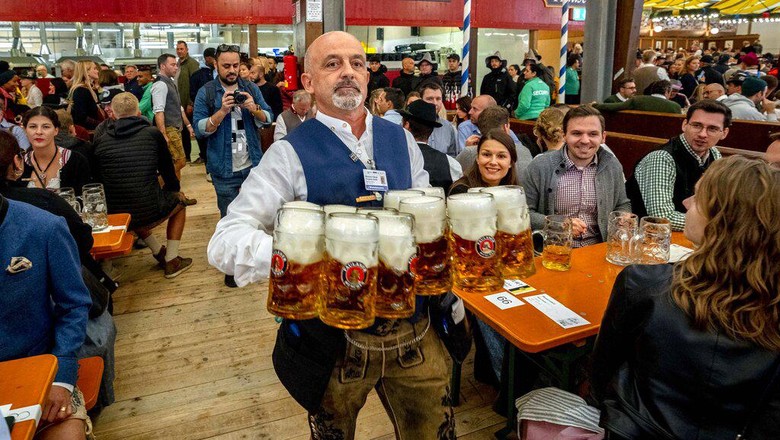 A waiter carries beer in one of the beer tents on the opening day of the 187th Oktoberfest beer festival in Munich, Germany, Saturday, Sept. 17, 2022. (AP Photo/Michael Probst)