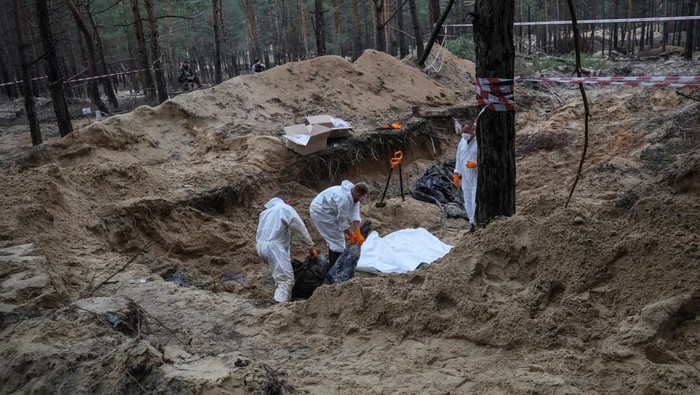 Members of Ukrainian Emergency Service carry a body as they work at a place of mass burial during an exhumation, as Russias attack on Ukraine continues, in the town of Izium, recently liberated by Ukrainian Armed Forces, in Kharkiv region, Ukraine September 17, 2022.  REUTERS/Gleb Garanich