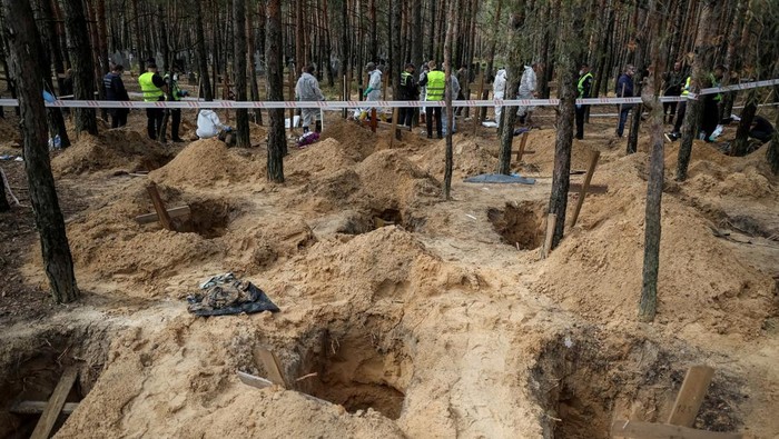 Members of Ukrainian Emergency Service carry a body as they work at a place of mass burial during an exhumation, as Russias attack on Ukraine continues, in the town of Izium, recently liberated by Ukrainian Armed Forces, in Kharkiv region, Ukraine September 17, 2022.  REUTERS/Gleb Garanich