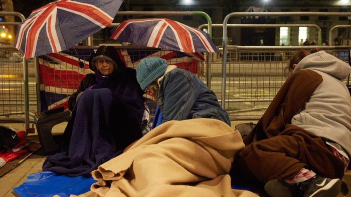 LONDON, ENGLAND - SEPTEMBER 19: People rest during a pause in movement as the last stretch of a days-long queue passes along the South Bank on September 19, 2022 in London, United Kingdom. Elizabeth Alexandra Mary Windsor was born in Bruton Street, Mayfair, London on 21 April 1926. She married Prince Philip in 1947 and acceded to the throne of the United Kingdom and Commonwealth on 6 February 1952 after the death of her Father, King George VI. Queen Elizabeth II died at Balmoral Castle in Scotland on September 8, 2022, and is succeeded by her eldest son, King Charles III. (Photo by Alex McBride/Getty Images)