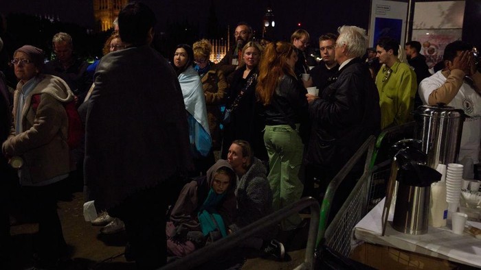 Lelah Saat Antre Saksikan Pemakaman Ratu Elizabeth, Warga Duduk dan Tidur di Jalan LONDON, ENGLAND - SEPTEMBER 19: People rest during a pause in movement as the last stretch of a days-long queue passes along the South Bank on September 19, 2022 in London, United Kingdom. Elizabeth Alexandra Mary Windsor was born in Bruton Street, Mayfair, London on 21 April 1926. She married Prince Philip in 1947 and acceded to the throne of the United Kingdom and Commonwealth on 6 February 1952 after the death of her Father, King George VI. Queen Elizabeth II died at Balmoral Castle in Scotland on September 8, 2022, and is succeeded by her eldest son, King Charles III. (Photo by Alex McBride/Getty Images)