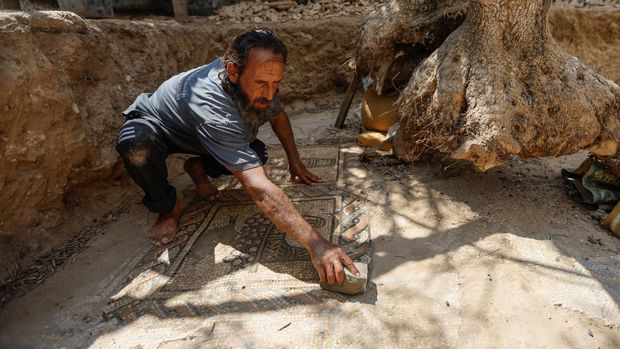 Petani Palestina Salman al-Nabahin membersihkan lantai mosaik yang ia temukan di pertaniannya dan berasal dari era Bizantium, menurut para pejabat, di Jalur Gaza tengah 18 September 2022. (REUTERS/IBRAHEEM ABU MUSTAFA)