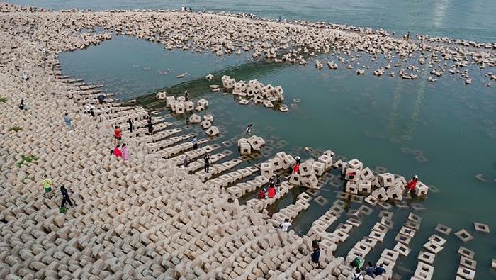 CHONGQING, CHINA - SEPTEMBER 17: Women pose for photos on ecological revetment bricks which are exposed along the Yangtze River on September 17, 2022 in Chongqing, China. The water level of Yangtze River has dropped due to sustained high temperatures and little rain. (Photo by Li Hongbo/VCG via Getty Images)