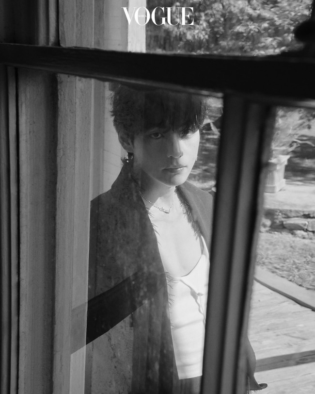 Tampil misterius dengan filter hitam putih. V BTS memakai blazer dan celana hitam keluaran brand Magliano. Dalaman putih yang mengekspos dadanya itu merupakan koleksi brand Inggris, SS Daley. Dia memadukannya dengan ankle boots Hermès. Foto: dok. Vogue Korea