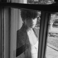 Tampil misterius dengan filter hitam putih. V BTS memakai blazer dan celana hitam keluaran brand Magliano. Dalaman putih yang mengekspos dadanya itu merupakan koleksi brand Inggris, SS Daley. Dia memadukannya dengan ankle boots Hermès. Foto: dok. Vogue Korea