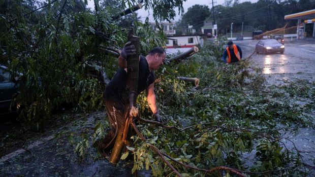 Warga membersihkan jalan dari pohon tumbang setelah Badai Fiona melanda daerah di Yauco, Puerto Rico 18 September 2022. (REUTERS/RICARDO ARDUENGO)
