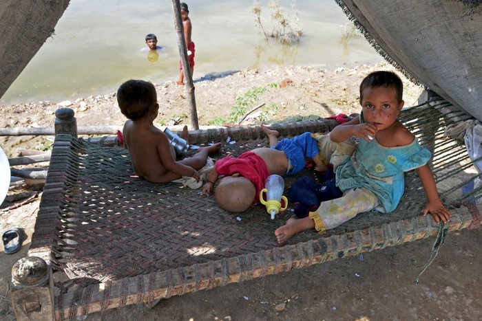 1243358332 A flood-affected family sits inside a temporary tent in a makeshift camp at Sohbatpur in Jaffarabad district of Balochistan province on September 19, 2022. (Photo by Fida HUSSAIN / AFP) (Photo by FIDA HUSSAIN/AFP via Getty Images)