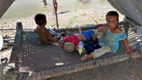 Anak-anak yang rumahnya terdampak banjir terlihat bermain di sekitar tenda darurat. Foto: AFP via Getty Images/FIDA HUSSAIN