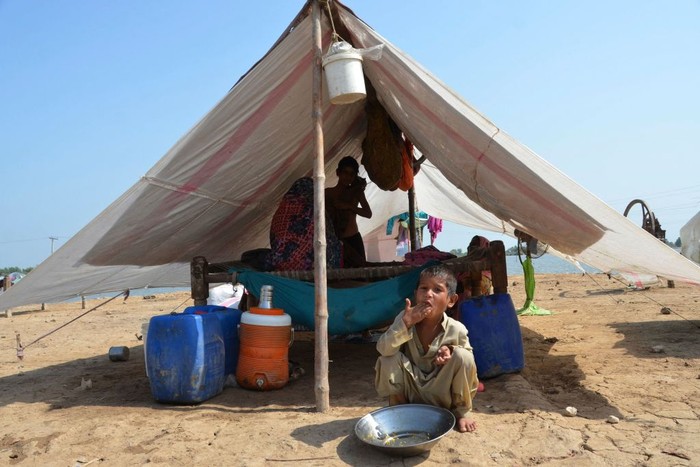 A flood-affected family sits inside a temporary tent in a makeshift camp at Sohbatpur in Jaffarabad district of Balochistan province on September 19, 2022. (Photo by Fida HUSSAIN / AFP) (Photo by FIDA HUSSAIN/AFP via Getty Images)