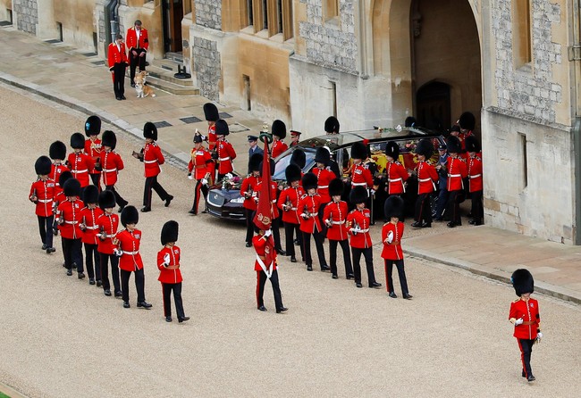Dijaga dua orang staf berseragam merah, Muick dan Sandy menantikan kedatangan peti Ratu Elizabeth II di salah satu sudut Kastil Windsor. Mereka sabar menunggu dengan tenang sampai akhirnya mobil jenazah yang membawa peti Ratu lewat di depan mereka. (Foto: Peter Nicholls - WPA Pool/Getty Images)