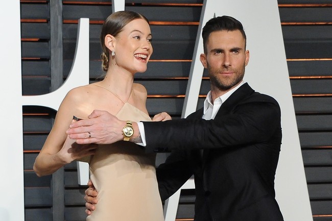 Behati Prinsloo hampir mengalami malafungsi busana di karpet merah Oscar After-Party Vanity Fair 2015. Adam Levine langsung turun tangan untuk melindunginya. (Foto: Getty Images)
