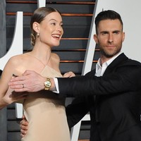 Behati Prinsloo hampir mengalami malafungsi busana di karpet merah Oscar After-Party Vanity Fair 2015. Adam Levine langsung turun tangan untuk melindunginya. (Foto: Getty Images)