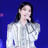 Salah satu gayanya yang jadi perbincangan adalah ala militer berikut ini. IU mengenakan atasan berkesan maskulin dipadukan dengan dress bernuansa peach yang kontras sehingga unik. Foto: Dok. Fansite Blueming