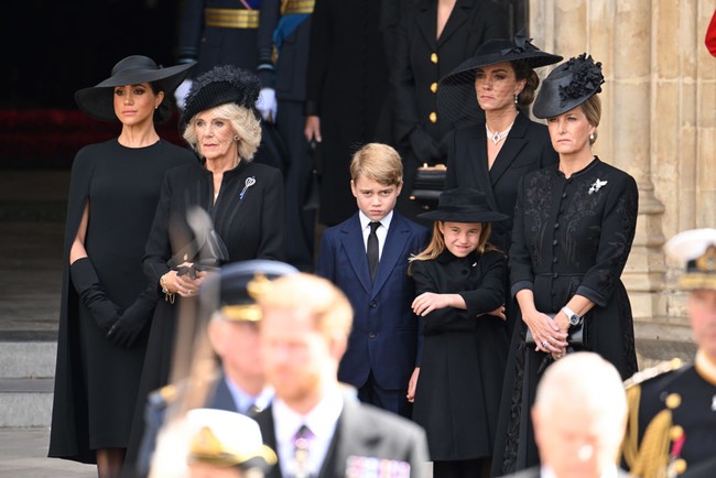 Inilah momen Meghan Markle menangis di sela-sela prosesi pemakaman Ratu Elizabeth II. Meghan tertangkap kamera menangis saat berdiri bersebelahan dengan permaisuri Camilla, Kate Middleton, Pangeran George dan Putri Charlotte. Foto: Dok. Getty Images, Wireimage